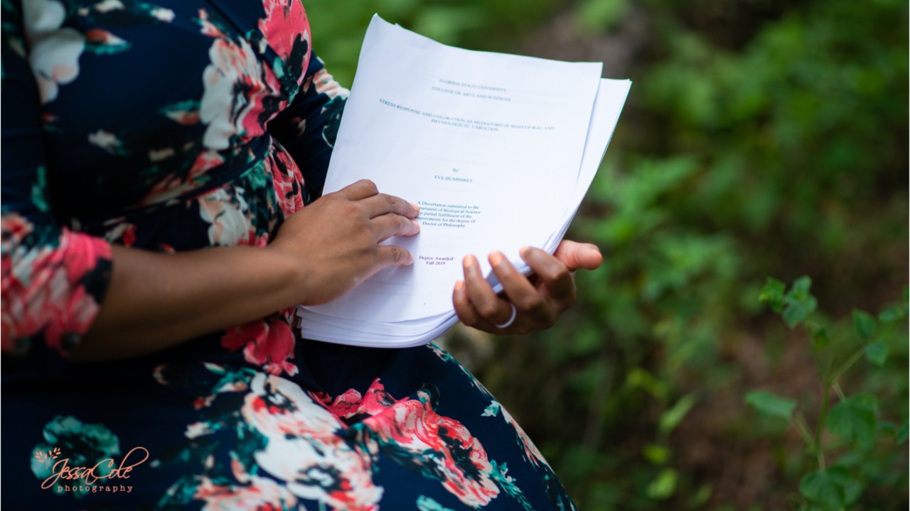 Woman holds dissertation in baby-style photo shoot