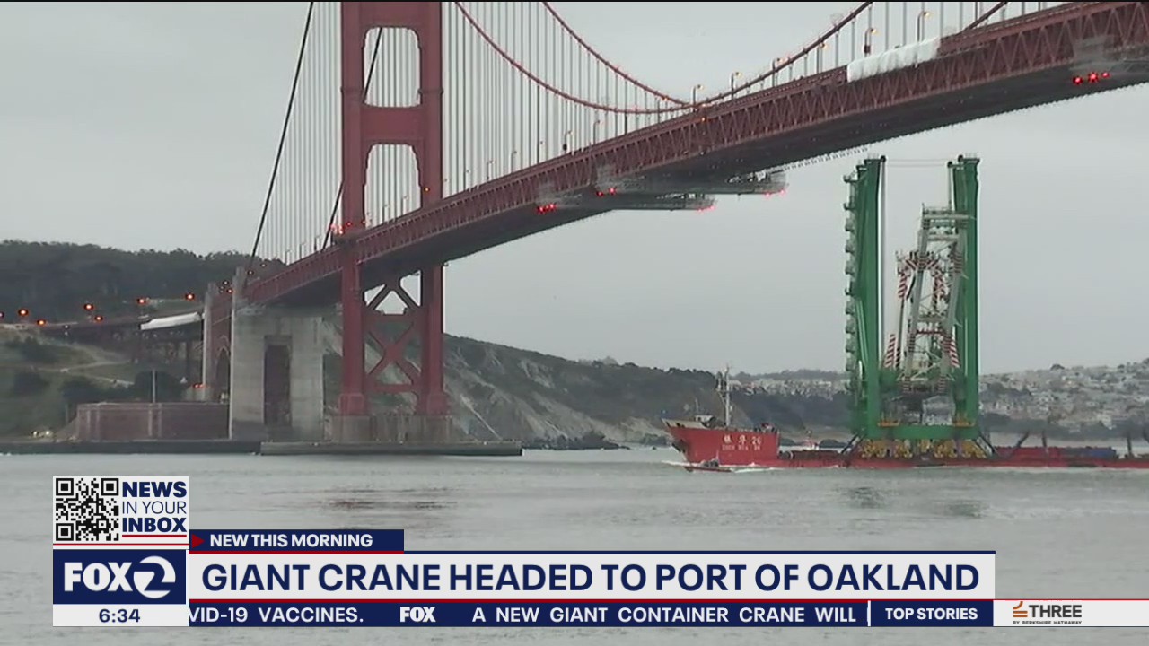 Cargo ship carrying giant crane sails under Golden Gate Bridge and Bay Bridge