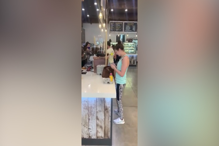 Maskless woman coughs on customer